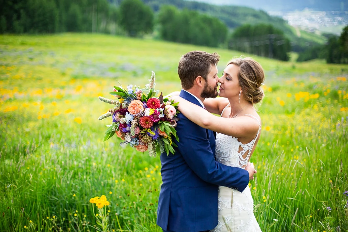 An elopement couple kisses in a yellow and purple wildflower field in the mountains of Crested Butte, Colorado.