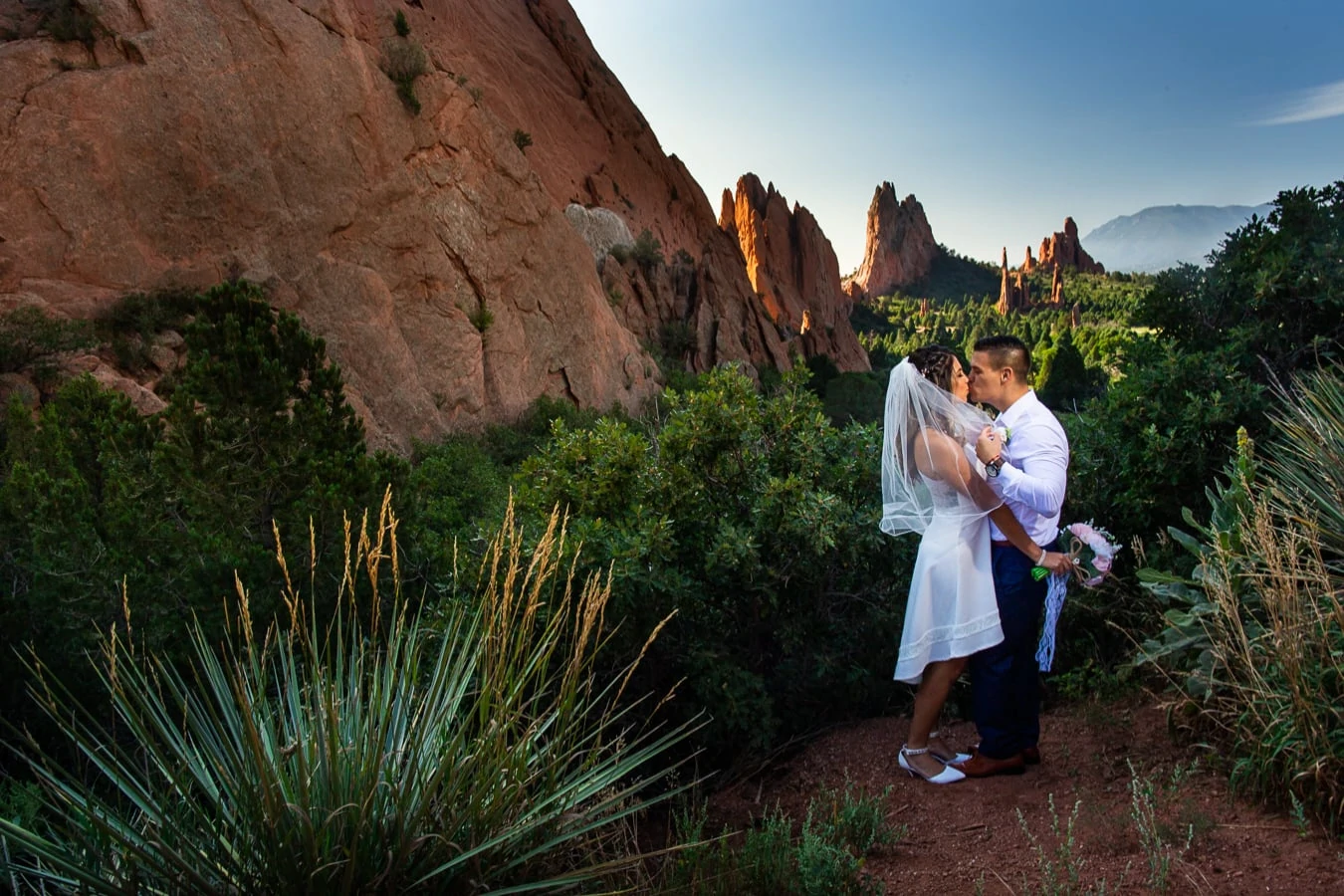 The elopement couple shares a smooch overlooking Garden of the Gods park at sunrise.