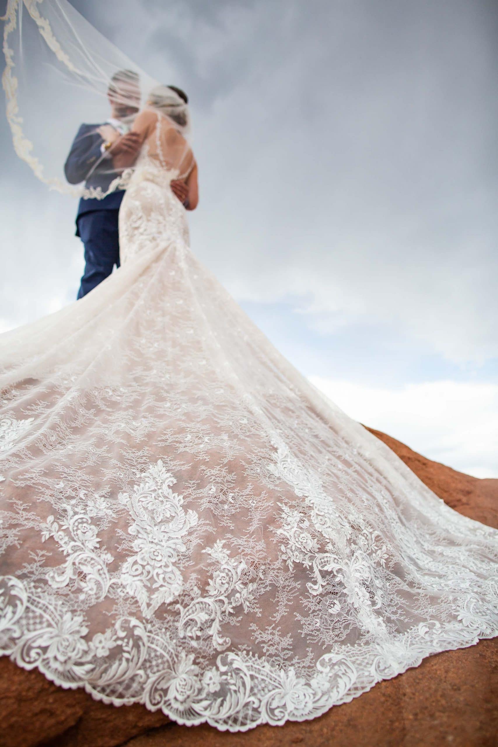 A close up of a lace wedding dress on a red rock at Garden of the Gods