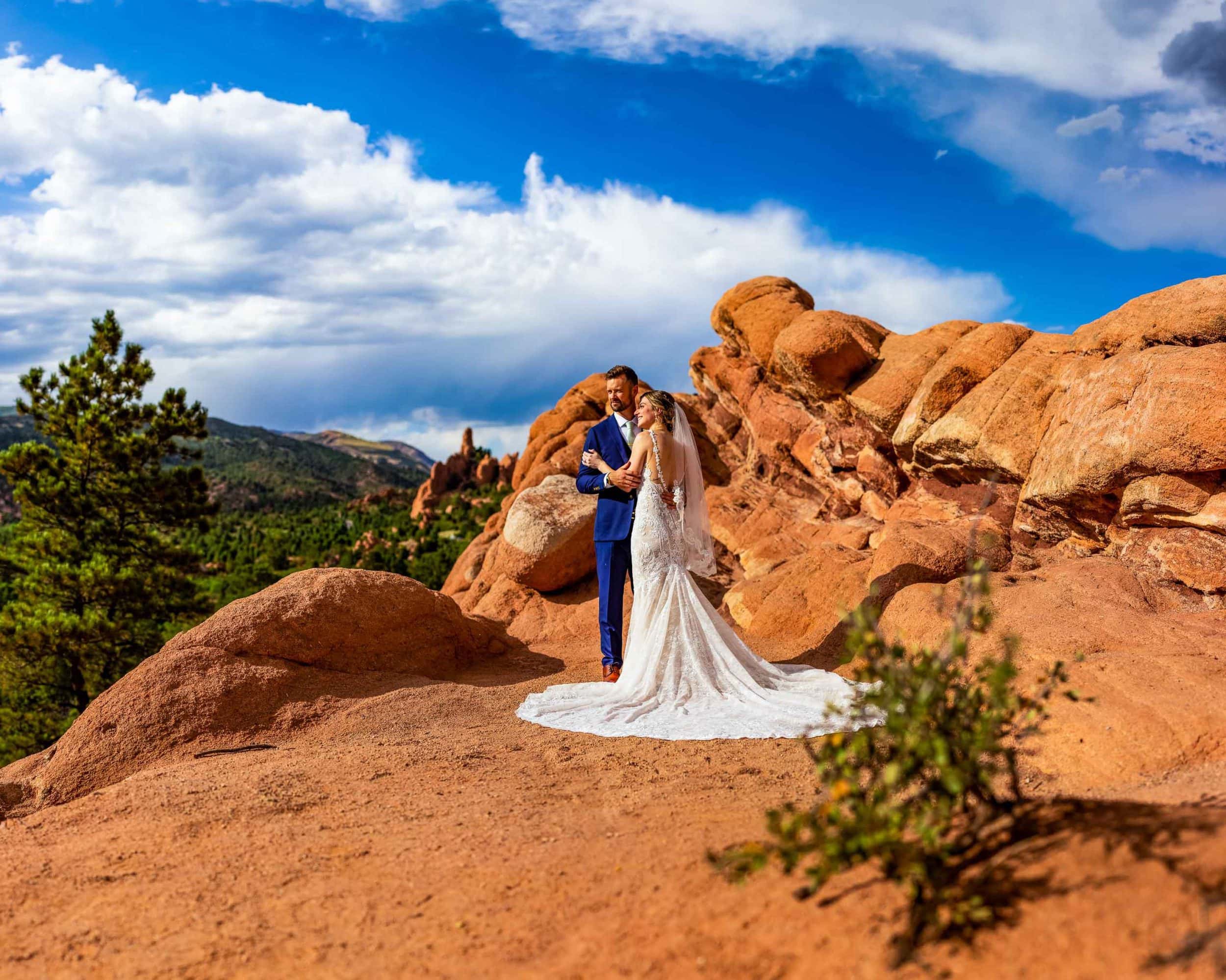 A wedding couple wearing a long white gown and a blue tuxedo faces the sunlight at Garden of the Gods at their colorado elopement in Colorado Springs.