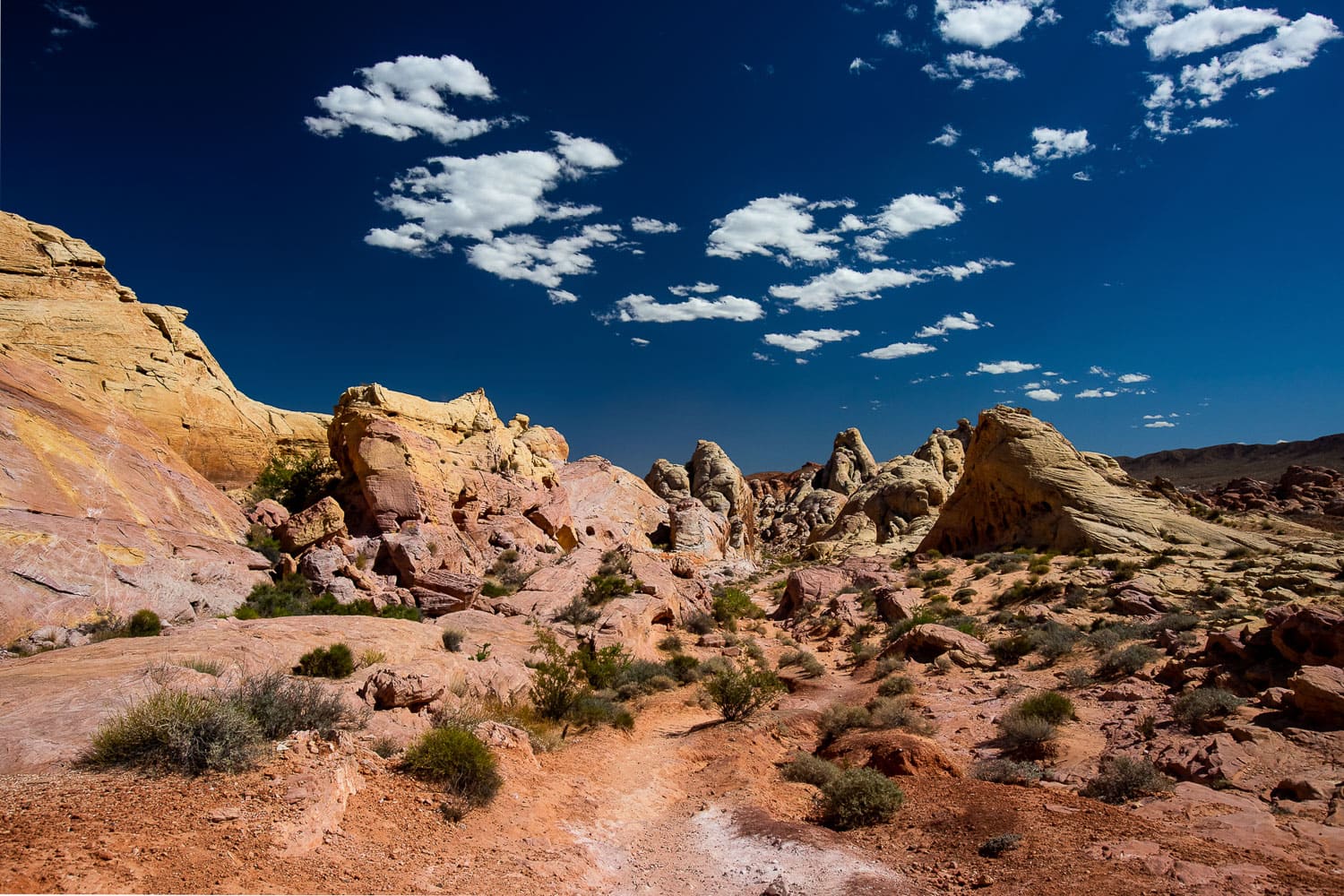 A desert landscape with yellow, pink, white, and orange rocks.