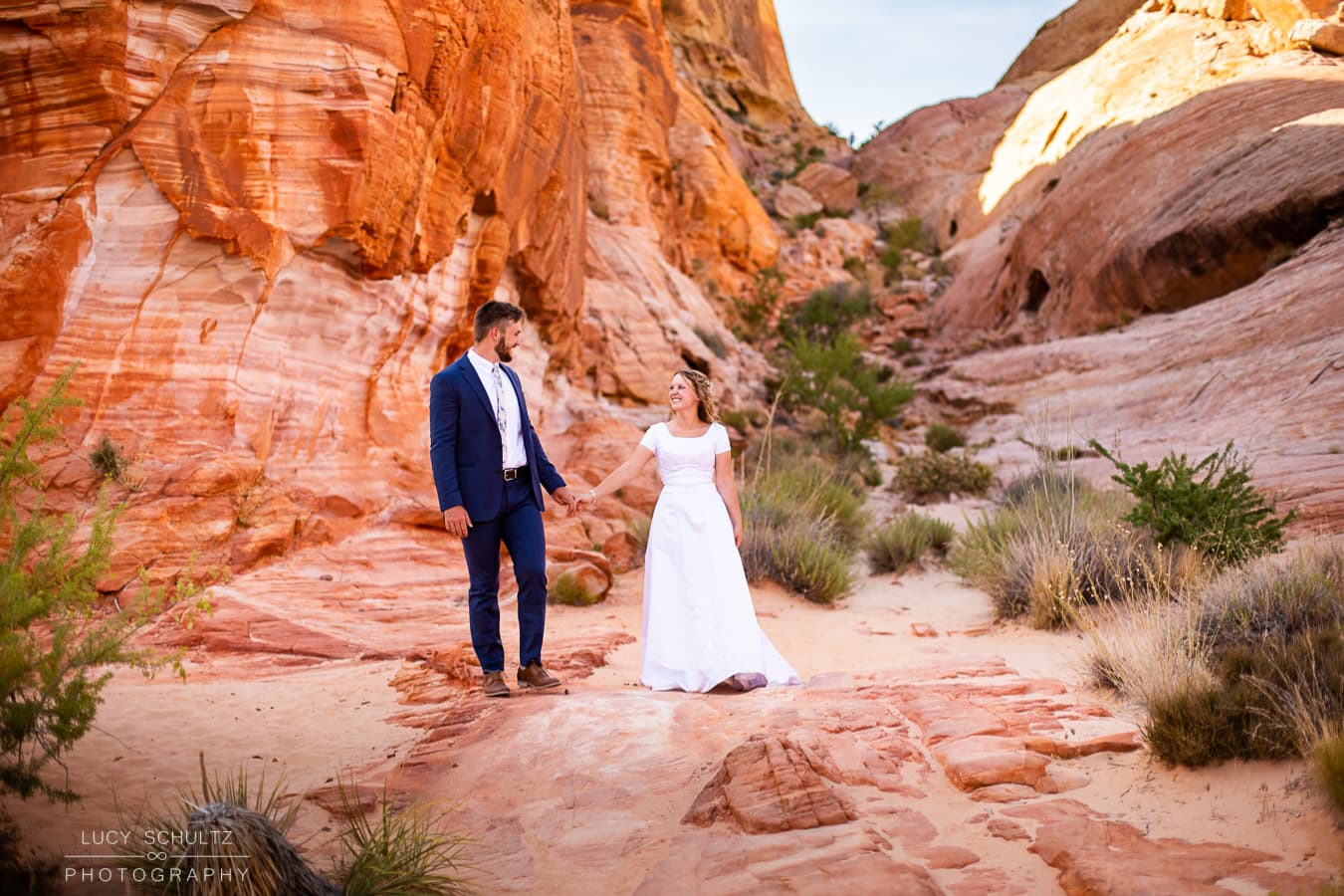 A bride and groom walk through the colorful desert rocks of Valley of Fire.