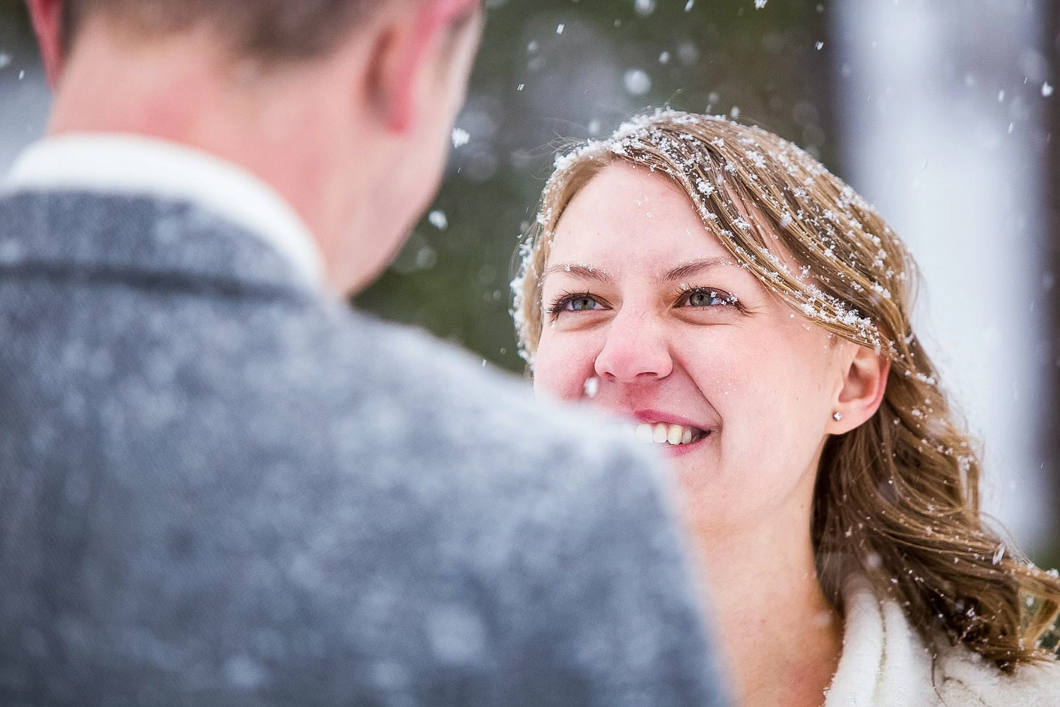 A bride looks at her spouse in a blizzard during their elopement ceremony.