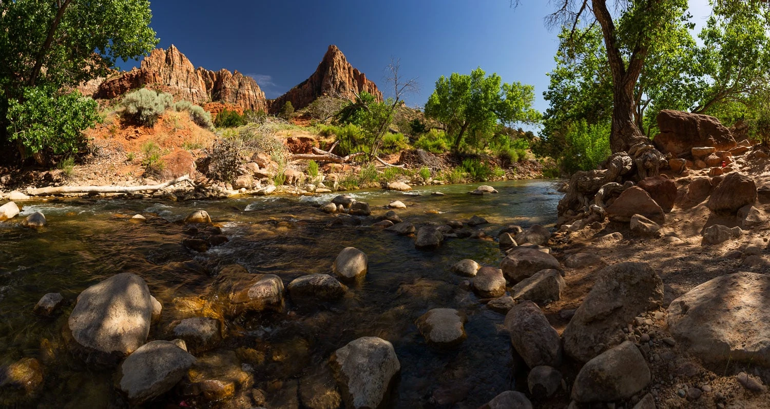 A peaceful looking river in front of The Watchman rock formation at Zion National Park.