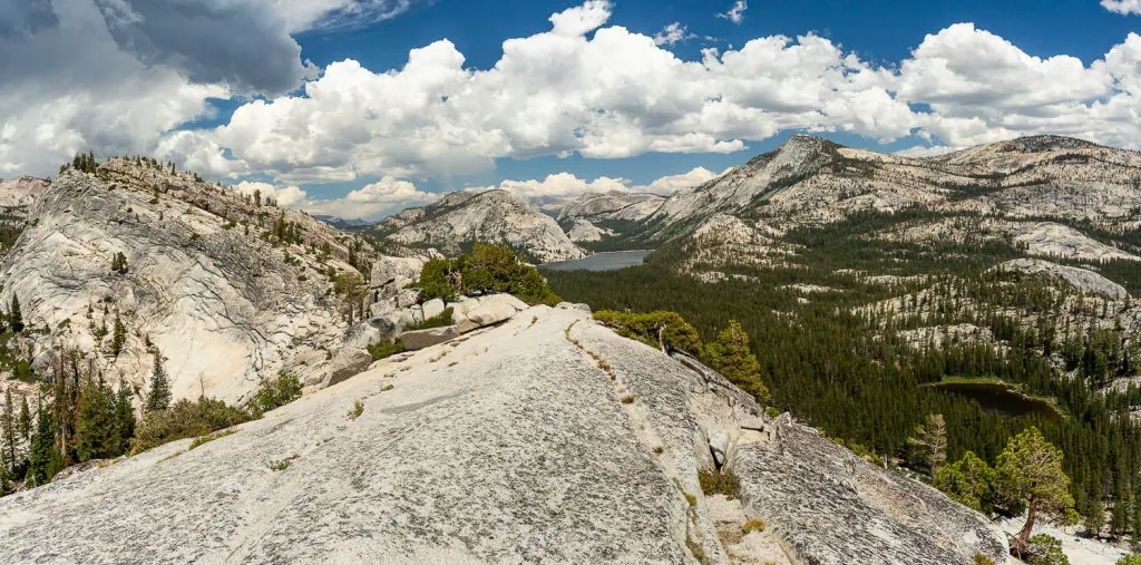 A gorgeous landscape photo taken along Tioga Road in Yosemite National Park in Summer, with mountains stretching towards a distant lake.
