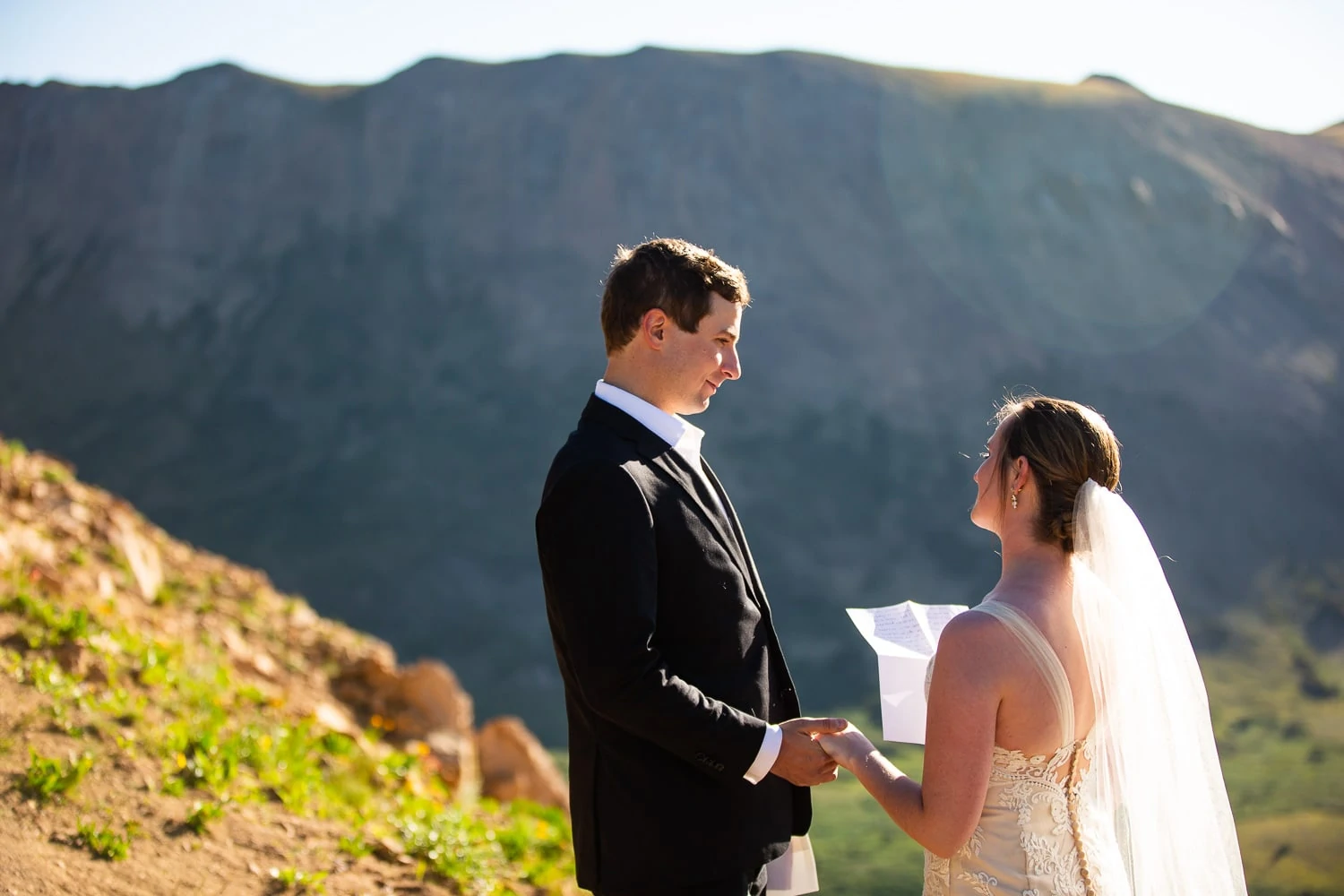 An elopement couple reads hand written vows to each other while hiking in the mountains.