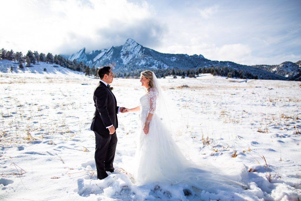 A wedding couple stands in front of the flatirons in boulder with a fresh coat of snow.
