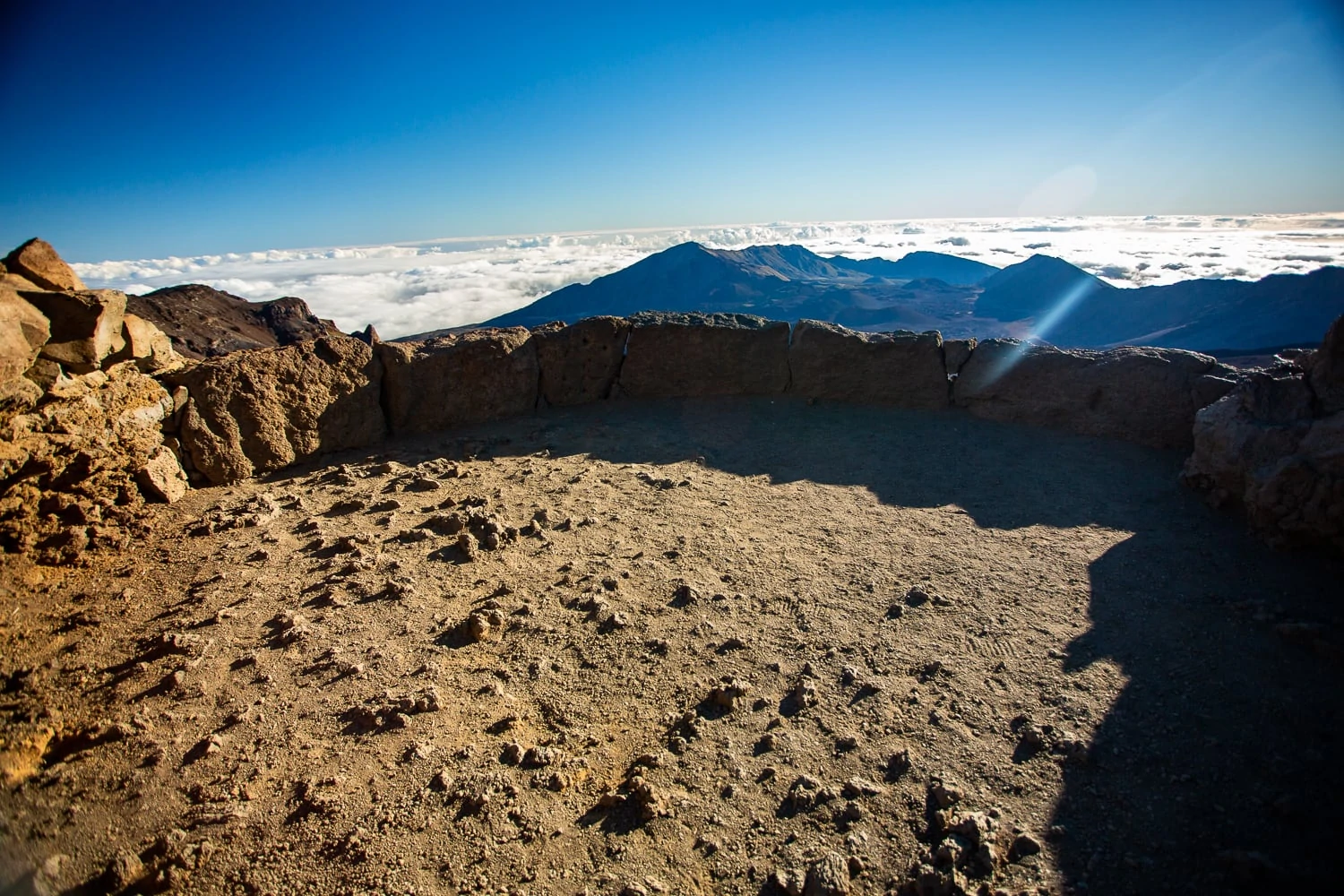 The white hill overlook at Haleakala's summit district, also known as Pa' Ka'oao, is shown here. A low stone wall separates the ceremony area from the volcano views below.
