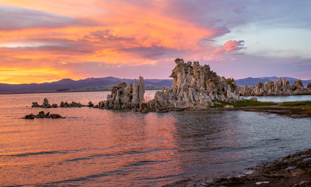 Mono Lake in Mono County, California at sunset with brown tufa formations in the lake. 
