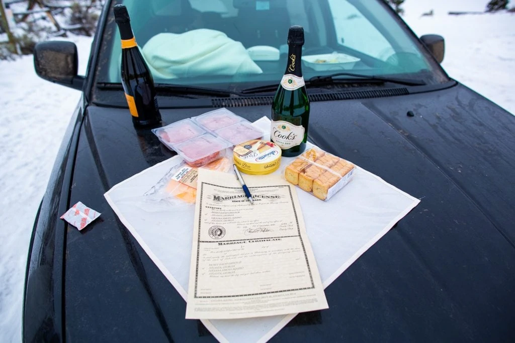 A charcuterie board and marriage license on the front of a car for an elopement couple.