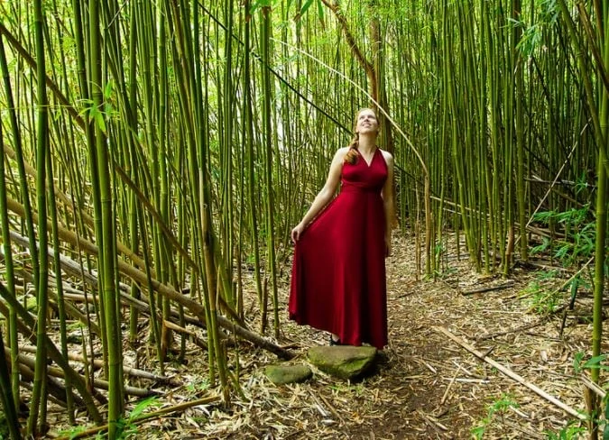 Haleakala elopement photographer Lucy Schultz poses in a red dress in the bamboo forest in Maui.