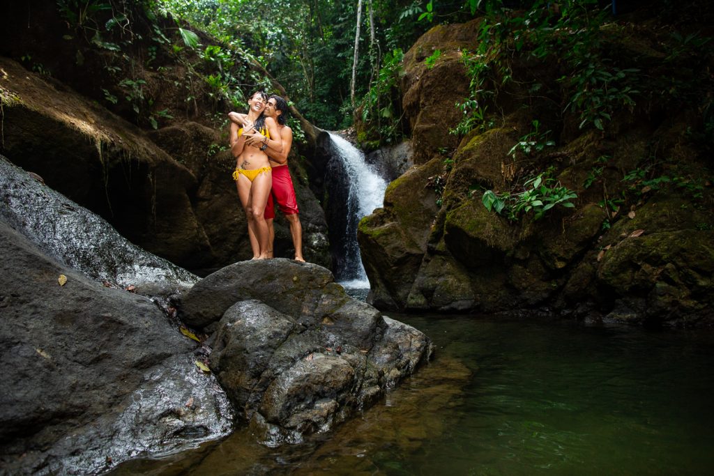 A couple kiss in front of a Costa Rica waterfall.
