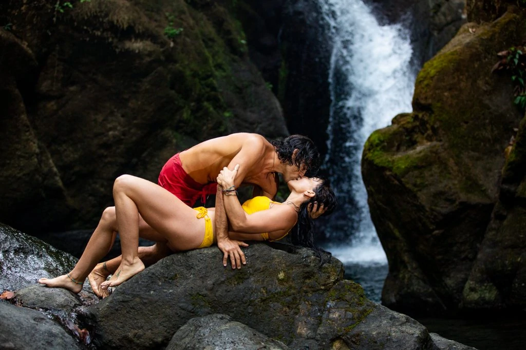 A steamy photo of a couple kissing under a waterfall in a tropical grove in Costa Rica.
