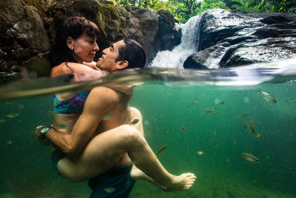 A split perspective photograph of a steamy couple embracing underwater at a waterfall in Costa Rica.