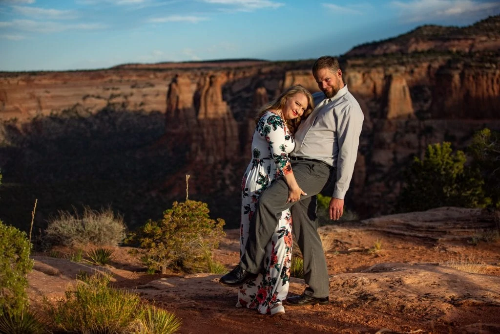A playful bride lifts the groom's leg in seductive pose on the edge of Colorado National Monument during their elopement photography.