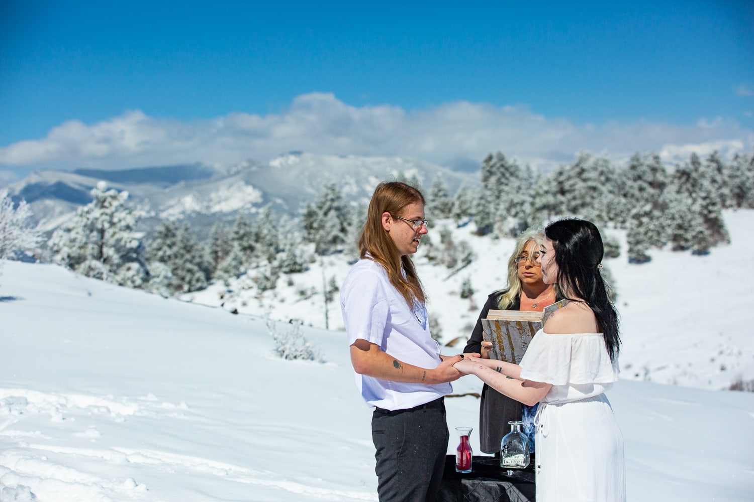 A bride and groom have an elopement ceremony in the winter on a mountainside.