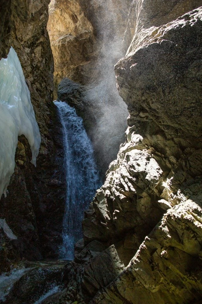 A vertical image of Zapata Falls in Blanca, Colorado, taken from inside the narrow canyon with ice around the falls.