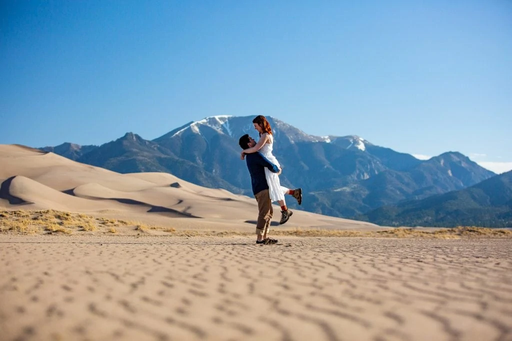 A romantic photo of a groom lifting his bride at their Great sand dunes elopement in May.