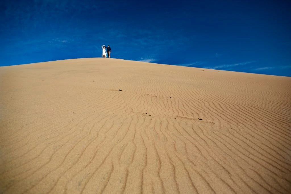 A dancing elopement couple at the top of a huge sand dune in Great Sand Dunes national park.