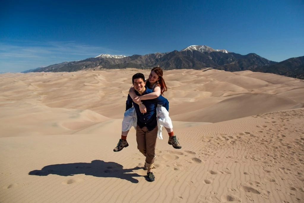 An elopement couple at the top of Great Sand Dunes highest dune with Medano peak in the background.
