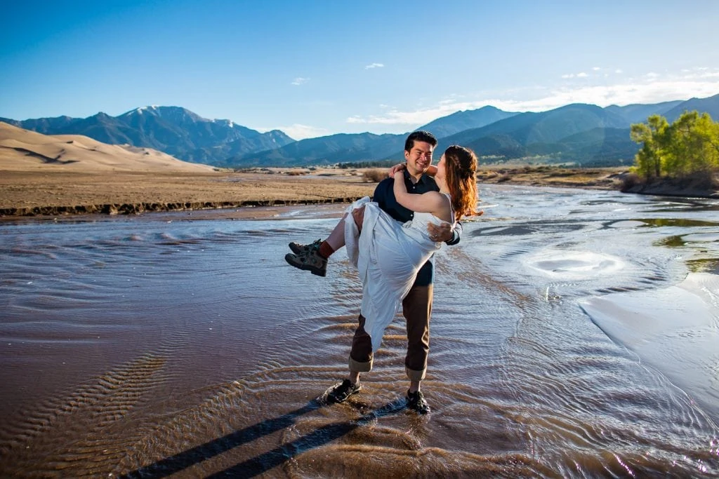 An elopement couple crossing Medano Creek in Great Sand Dunes National Park