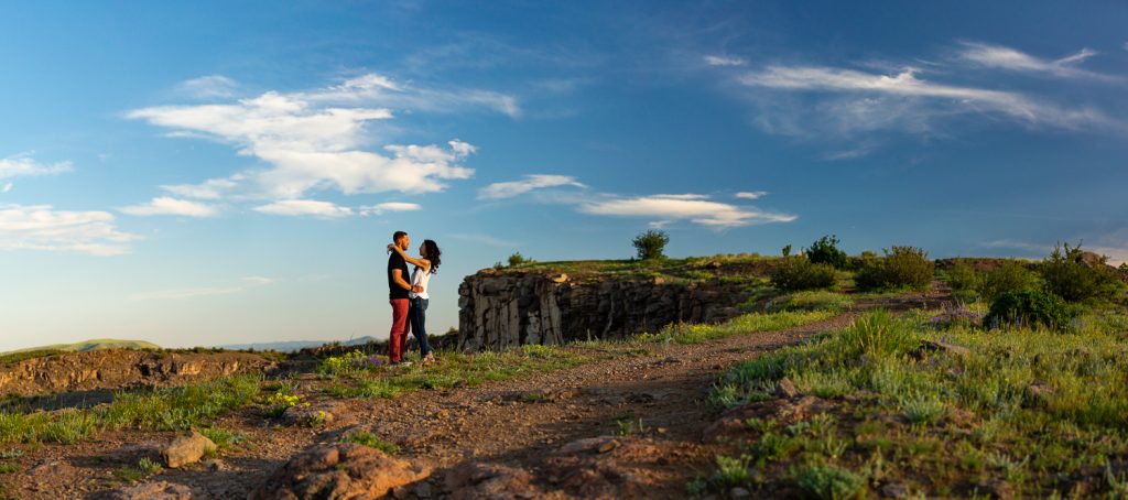 An engaged couple look at each other on top of North Table Mountain in Golden, Colorado.