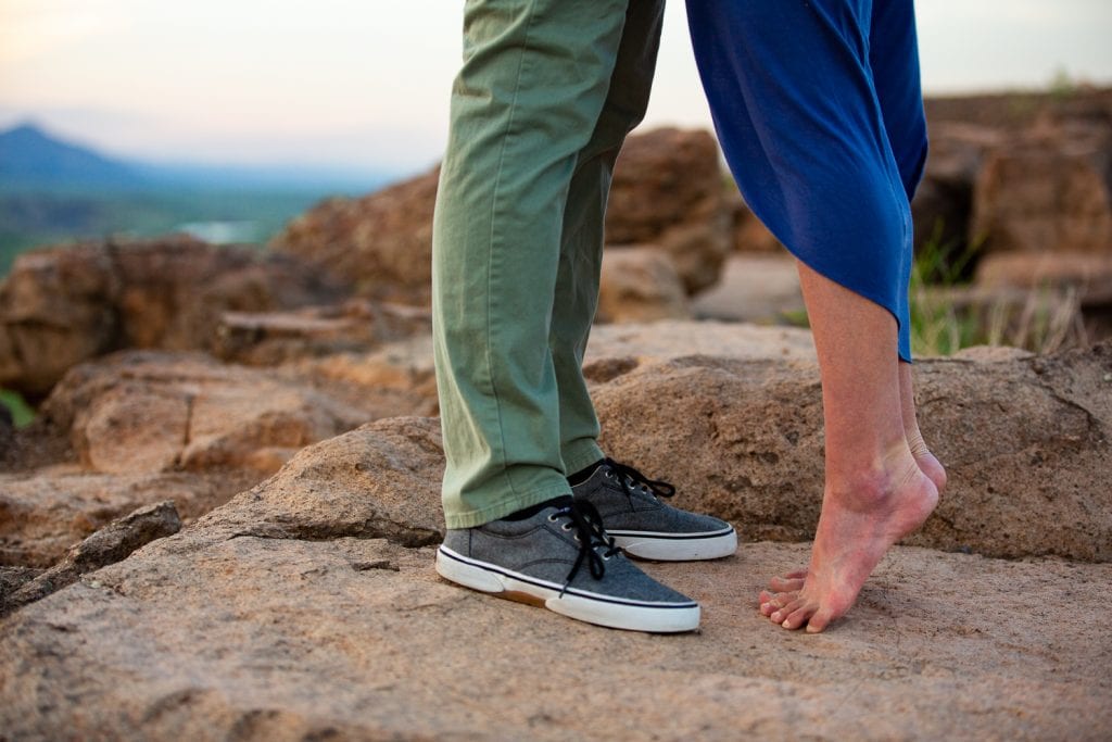 A cute engagement photo of a woman standing on her tip toes.