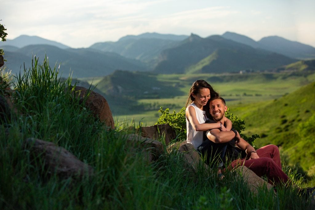 A woman hugs her man from behind above the city of Golden, Colorado in this colorful engagement photo