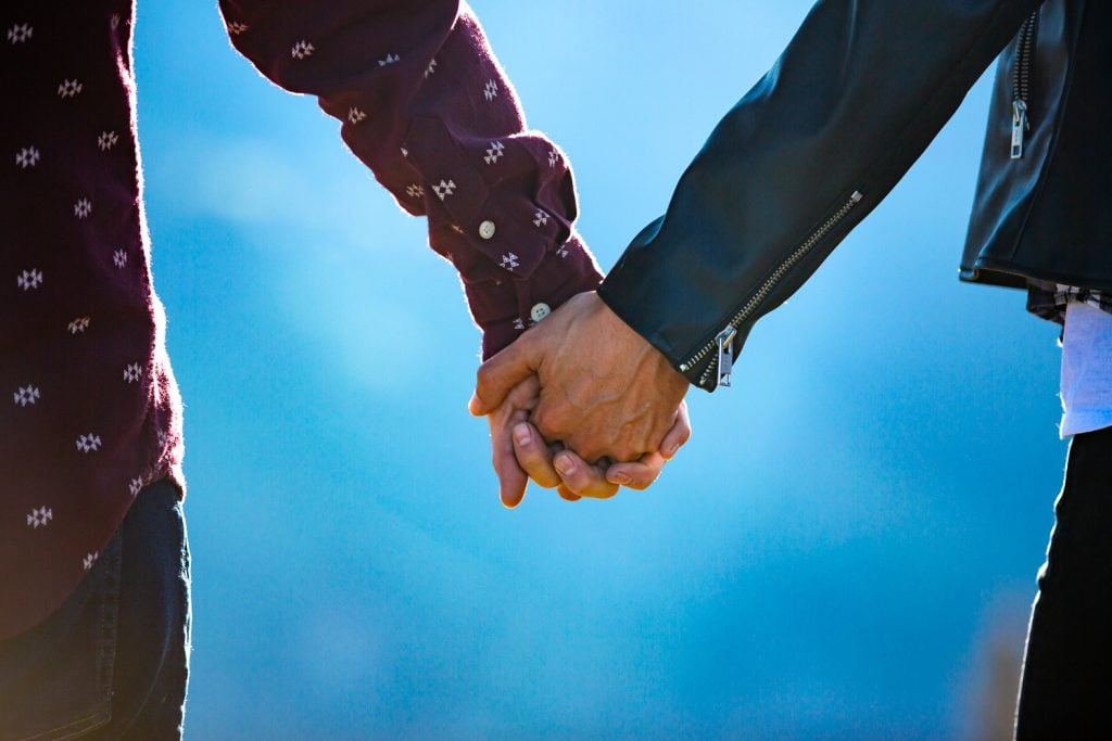 Two men hold hands at their engagement photo session in telluride.