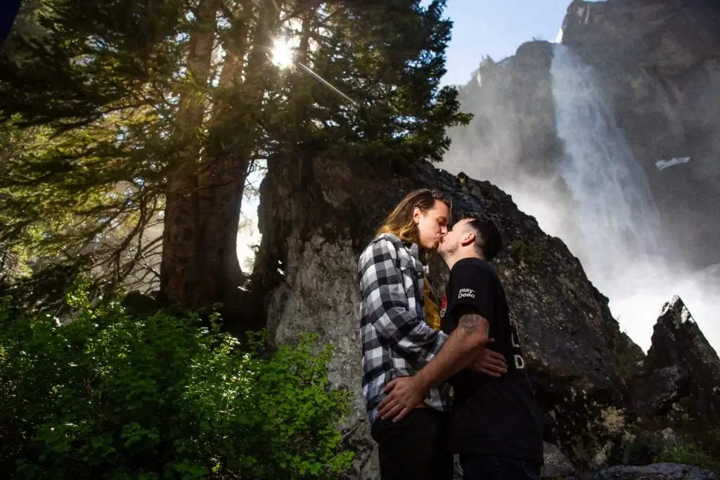 Two men kiss in this engagement photo in front of bridal veil falls in Telluride, Colorado