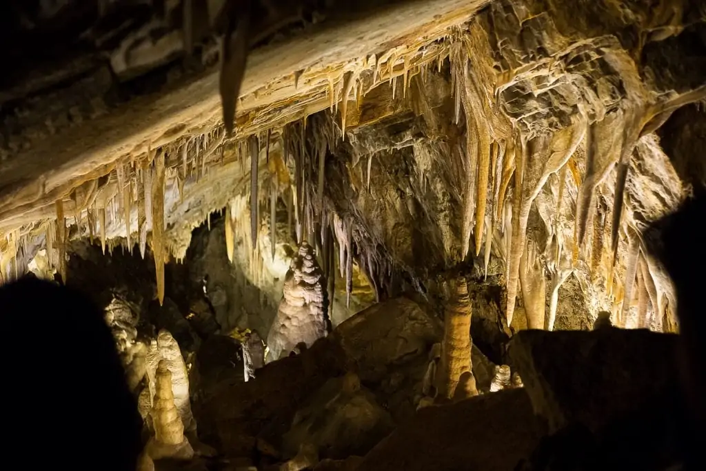 A lit up cave in Glenwood Springs, Colorado. Stalagtites glow in shades of yellow and brown.
