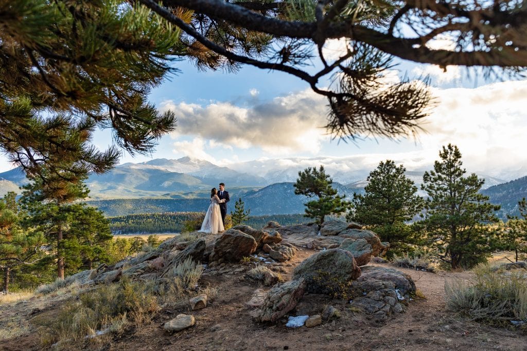 Big mountains surround a couple on some rocks in Estes Park during their elopement. 