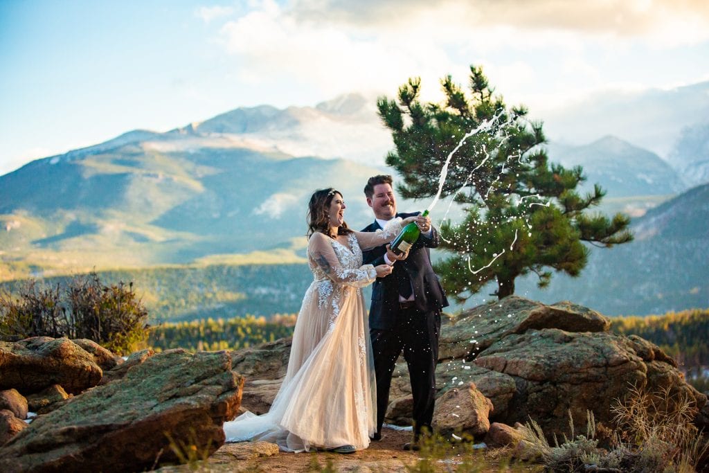 A couple sprays champagne at their alternative mountain elopement.