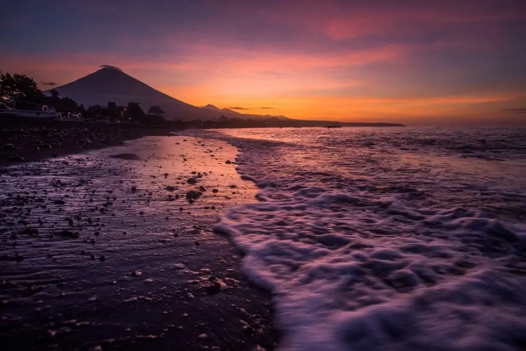 Purple sky is reflected in the ocean at sunset over Mt. Agung in Bali, indonesia.