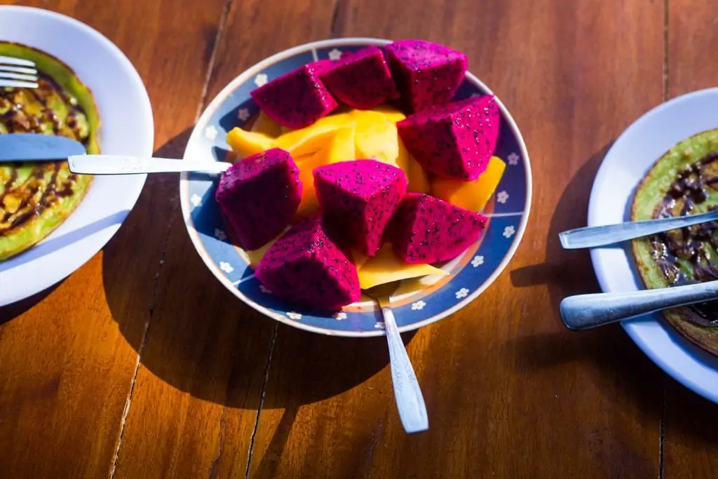 Bright pink dragonfruit and mango slices in a blue ornate bowl is a common breakfast in Bali.