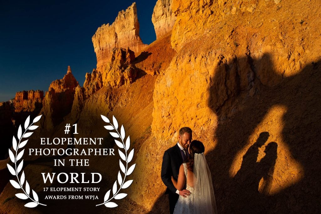 A photo of a bride and groom looking into each other's eyes in a dramatic, rocky, desert-like national park, with their silhouettes projected on the rock next to them, and the text "#1 elopement photographer in the world, 17 elopement story awards from WPJA" superimposed on the left of the image.