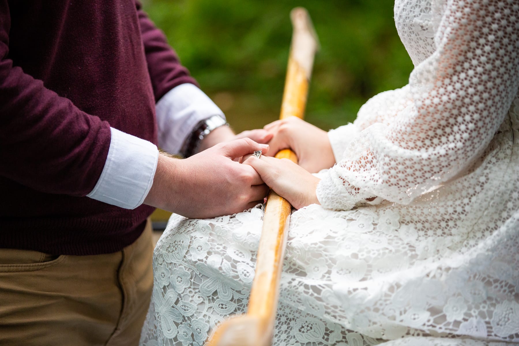 An elopement couple holds hands in a canoe over a paddle.