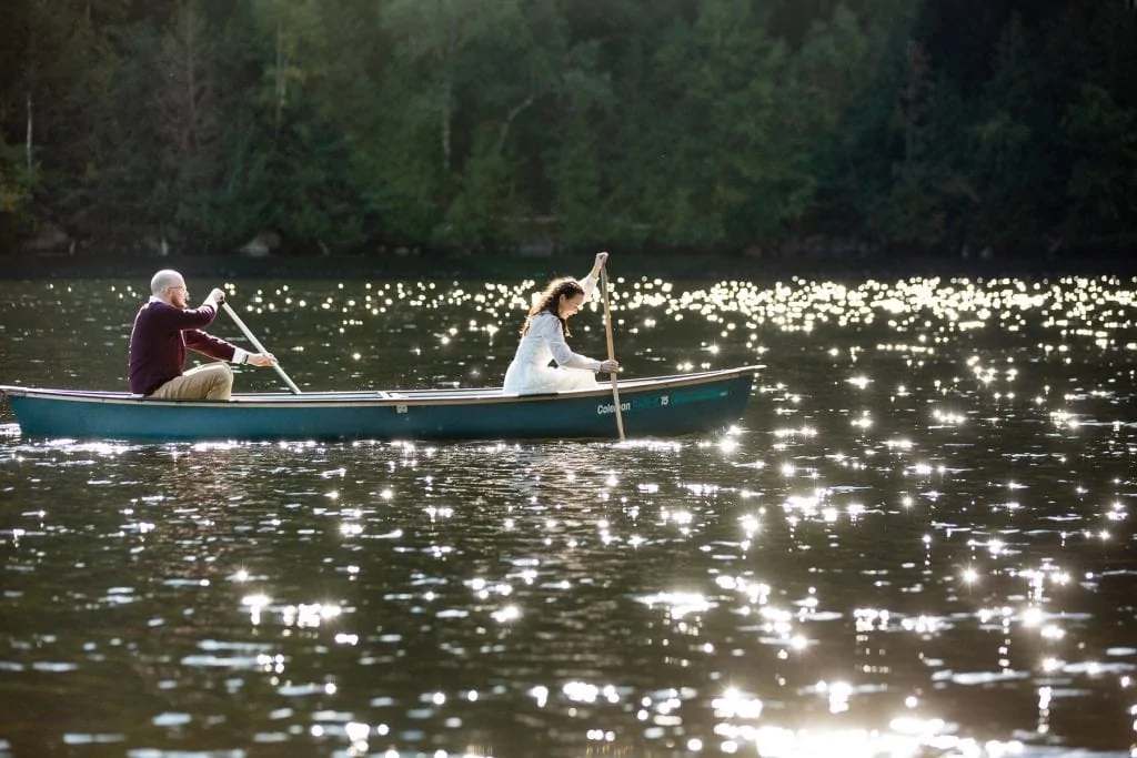 Sparkling lake water surrounds an elopement couple in a canoe.