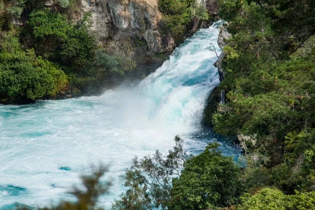 Huka falls is a thrashing, powerful waterfall with bright blue water.