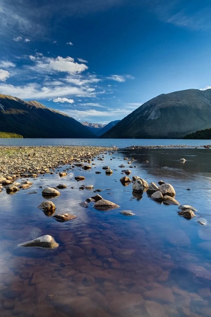 The shore of Lake Rotoroa in New Zealand is dotted with rocks.