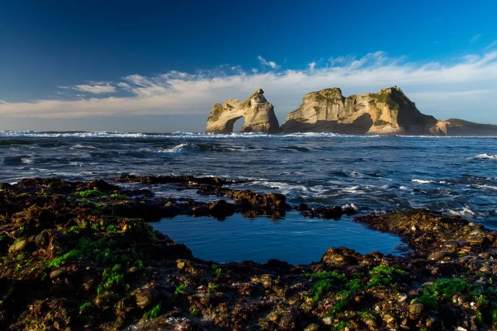 A tide pool in the foreground of Archway Islands rock formation in New Zealand.