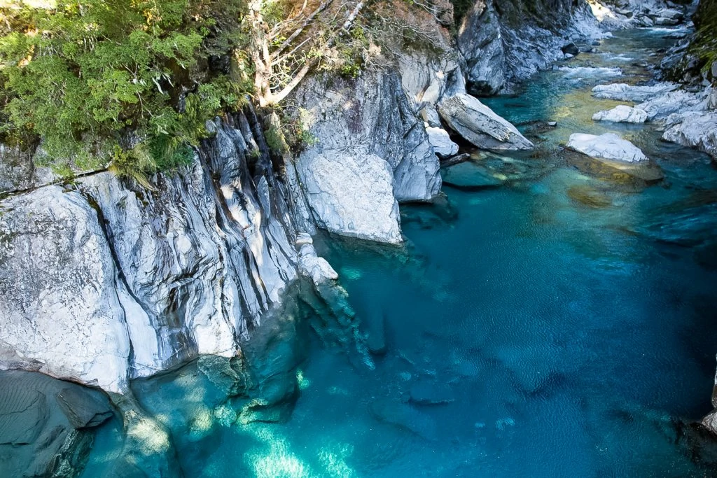 Clear blue water against grey rocks at the Blue Pools in New Zealand.