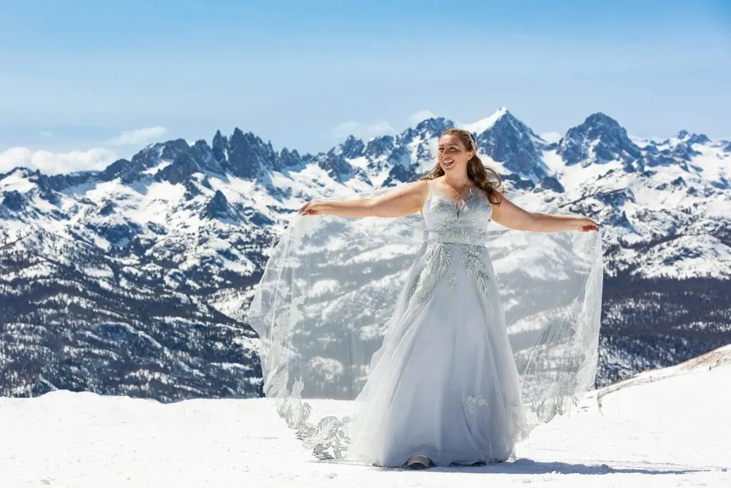 A bride spreads her cape veil at the top of Mammoth Mountain in California.