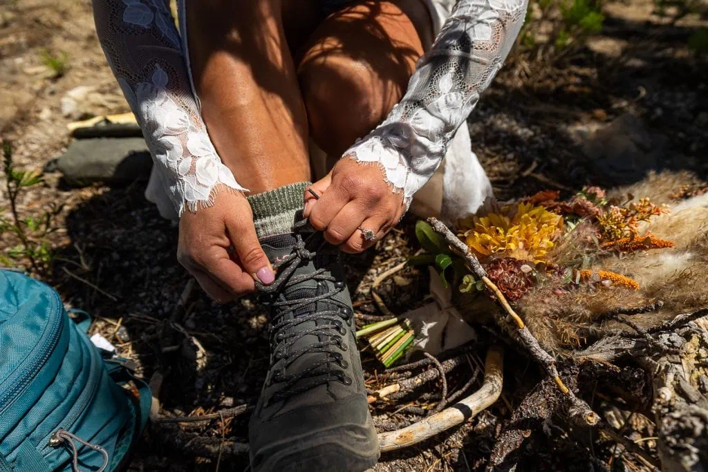 A yosemite elopement bride ties the laces on her hiking boots.