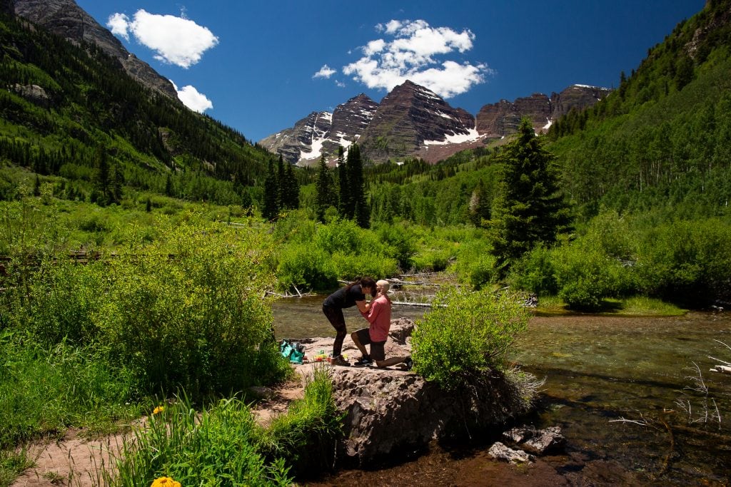 A man gets down on one knee and proposes to his girlfriend at the Maroon Bells.