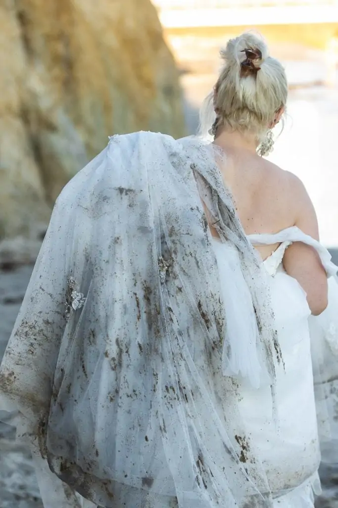 A bride's ballgown is muddy with sand after eloping on the beach in california.