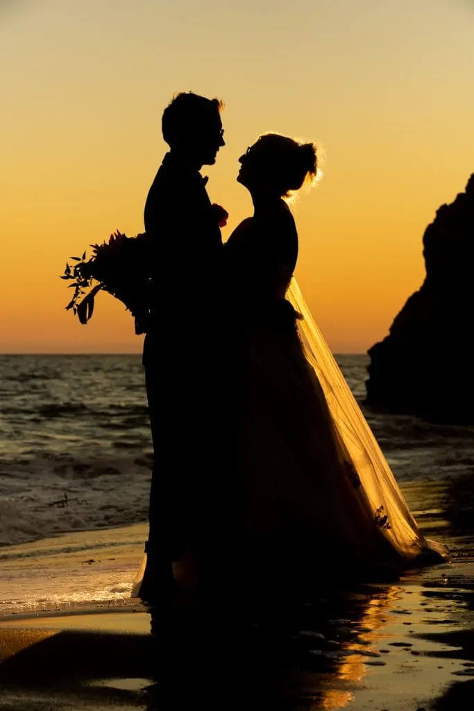A colorful silhouette of a bride and groom at the beach in Malibu, California.