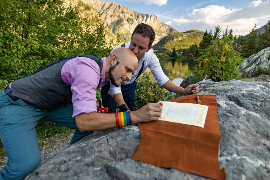 Two gay men sign their marriage license in the mountains while eloping.