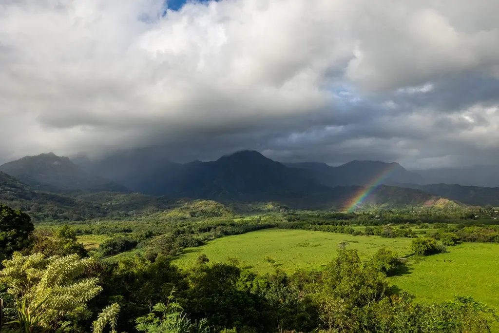 A view of Kauai's mountains from Hanalei, with a rainbow across the green valley.