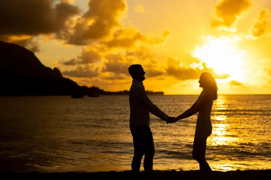 A silhouette of a couple holding hands by Kauai elopement photographer Lucy Schultz taken at Hanalei Bay.